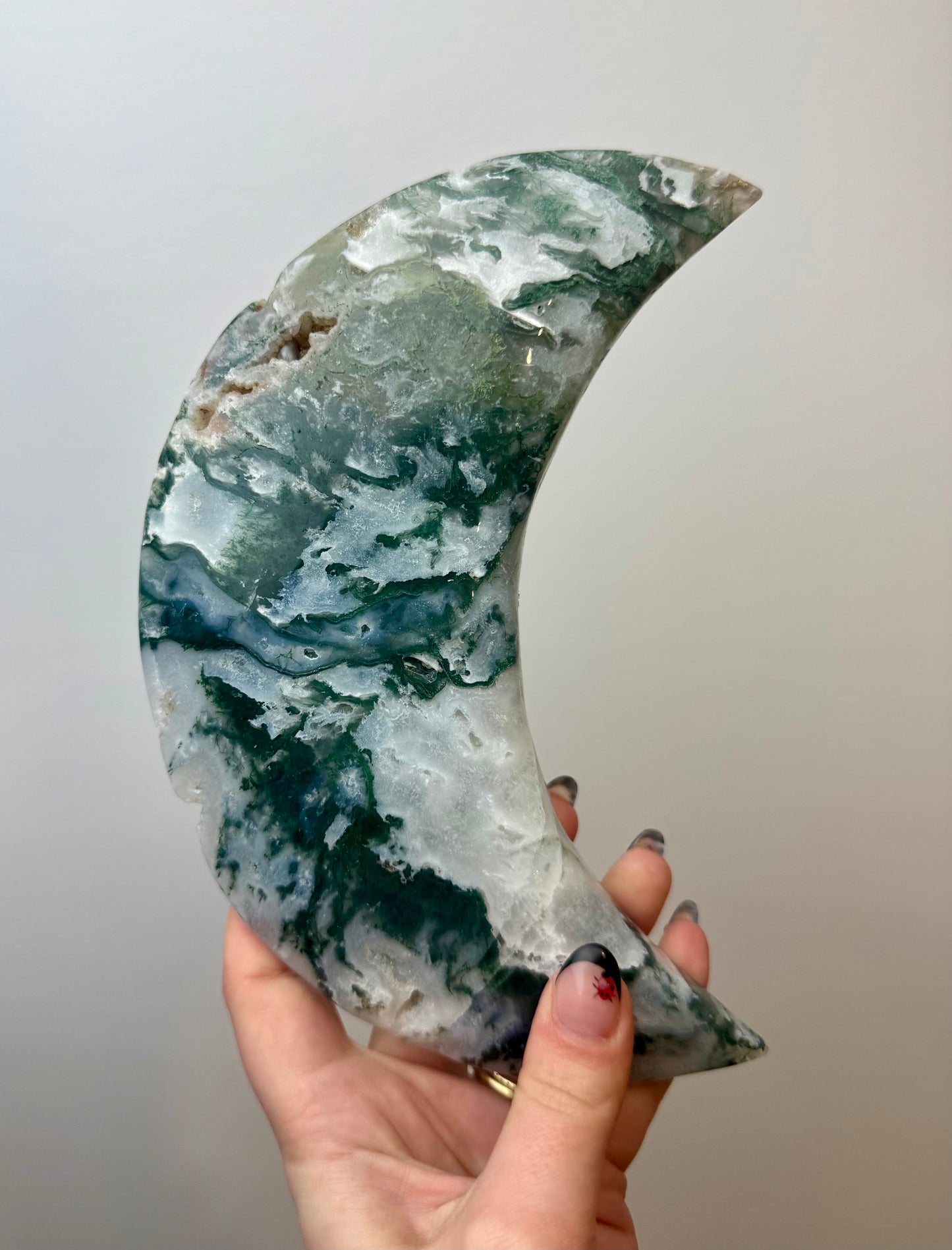 Moss agate moon carving on a stand