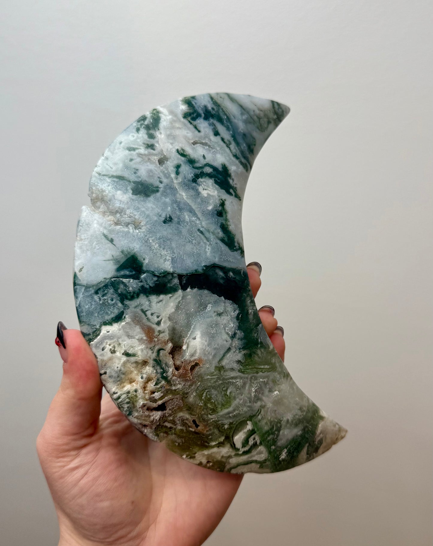Moss agate moon carving on a stand