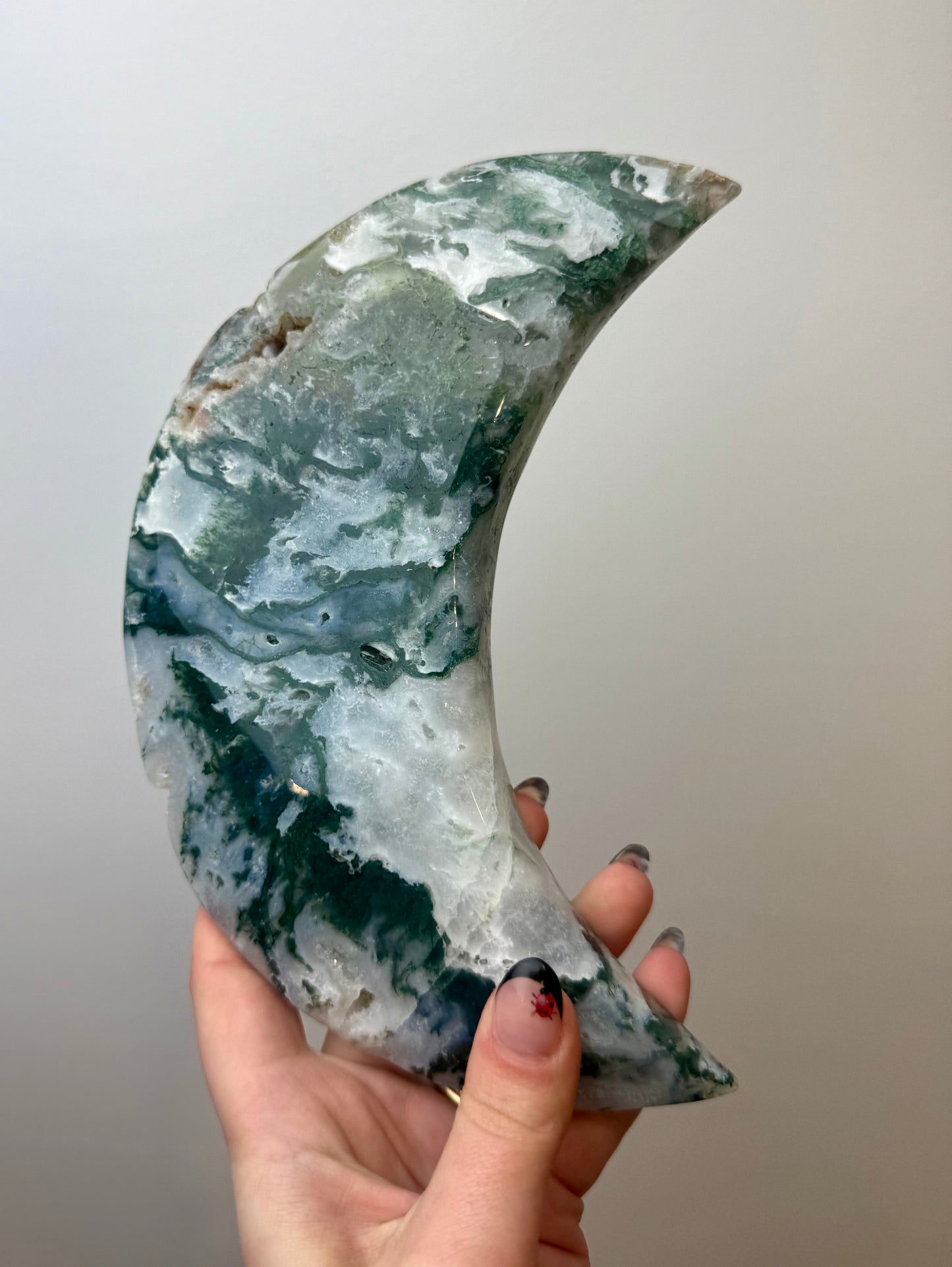 Moss agate moon carving on a stand