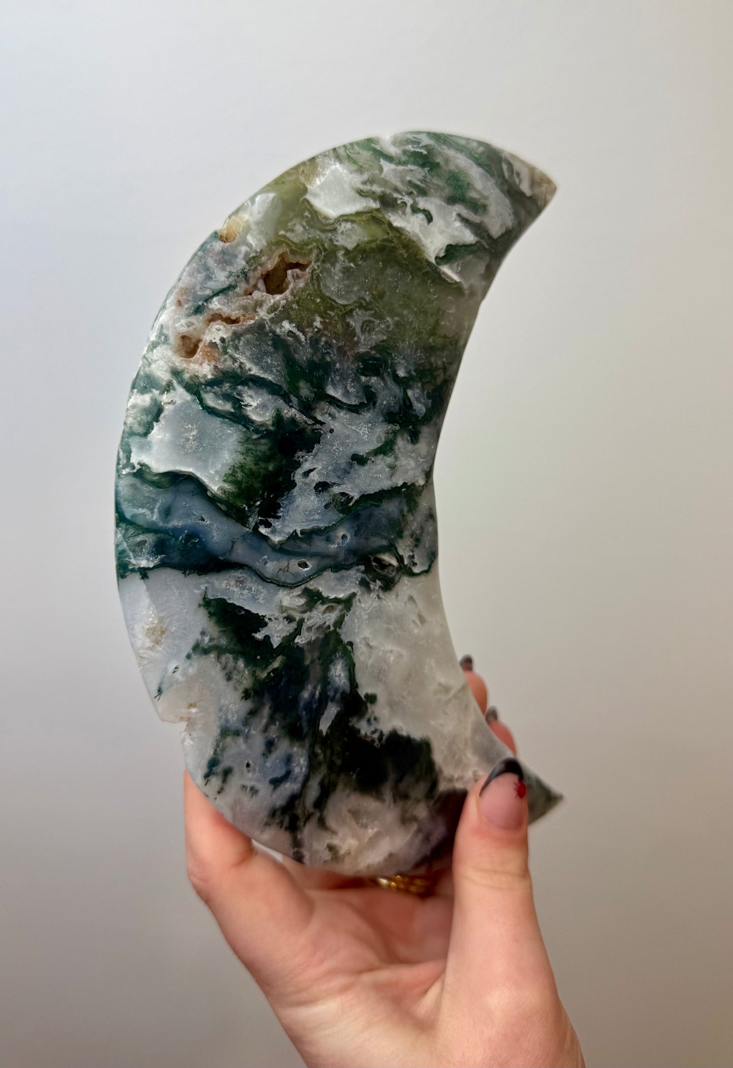 Moss agate moon carving on a stand