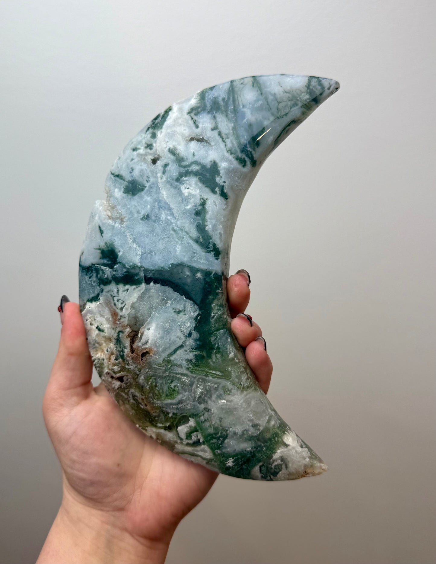 Moss agate moon carving on a stand