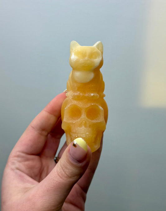 Orange calcite cat on skull carving